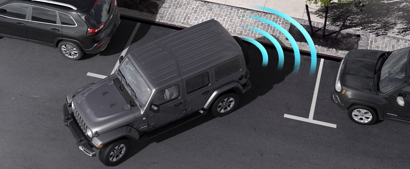 Illustration of sensors monitoring the area behind the 2021 Jeep Wrangler Sahara as it parallel parks at a curb.