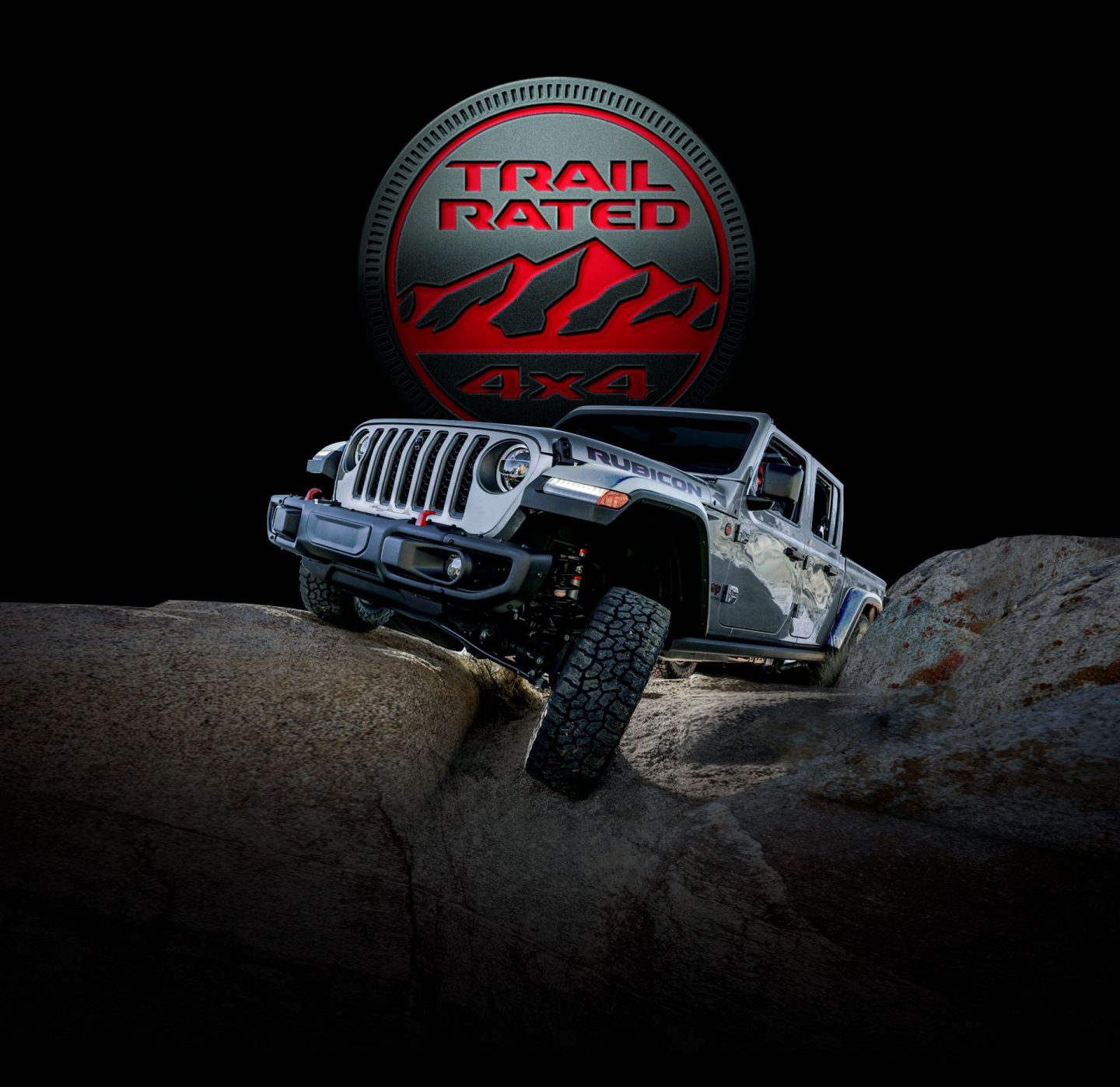 Trail Rated 4x4. The 2022 Jeep Gladiator Rubicon being driven on rocky terrain with one wheel elevated as it climbs a boulder.