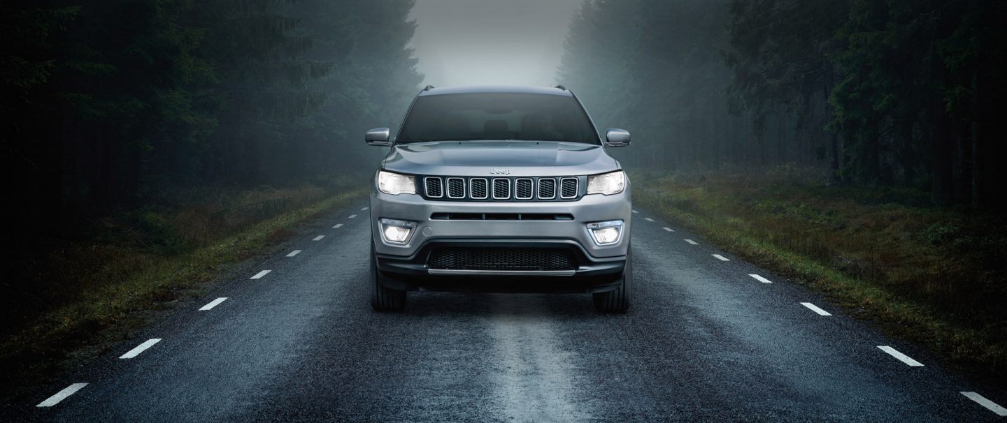 The 2021 Jeep Compass being driven in heavy rain on a winding road.