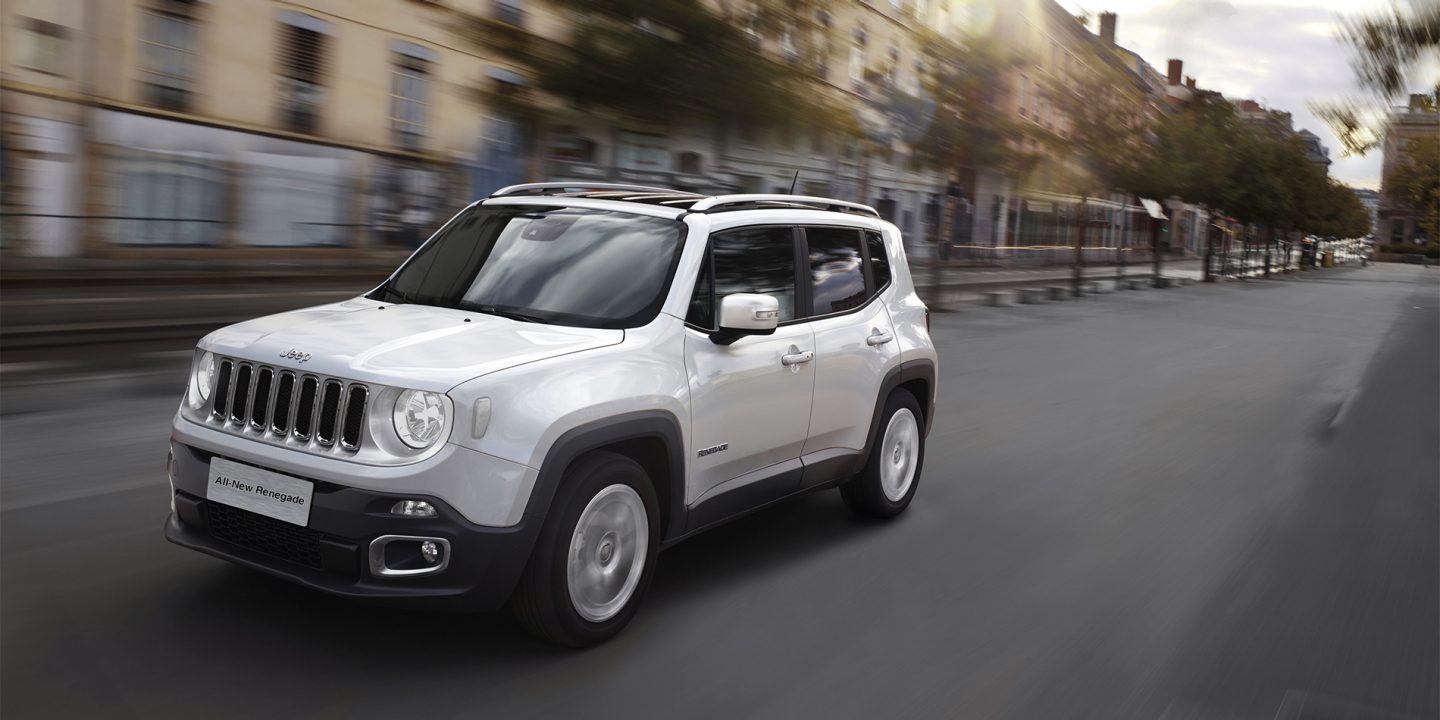 A red 2021 Jeep Renegade being driven through a tunnel with headlamps lit.